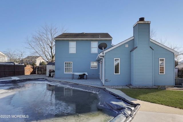 rear view of house with a fenced in pool, a fenced backyard, a patio, and a chimney