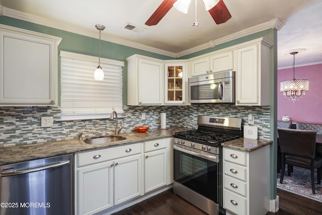 kitchen with glass insert cabinets, pendant lighting, stainless steel appliances, and a sink