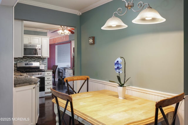 dining room featuring ceiling fan, ornamental molding, wainscoting, and dark wood finished floors