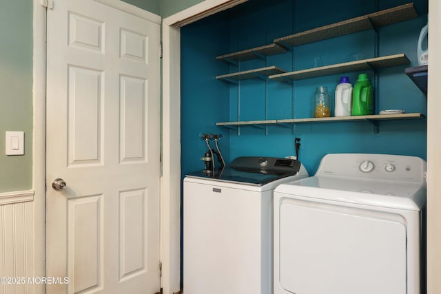 laundry room featuring a wainscoted wall and washer and clothes dryer