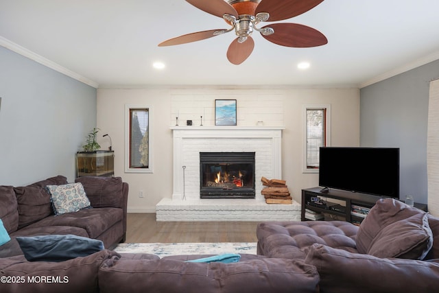 living area featuring a fireplace, crown molding, light wood finished floors, recessed lighting, and baseboards