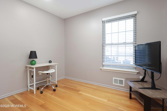 office space with wood finished floors, visible vents, and baseboards