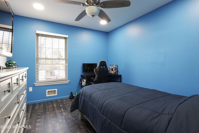 bedroom featuring dark wood-style floors, ceiling fan, visible vents, and baseboards