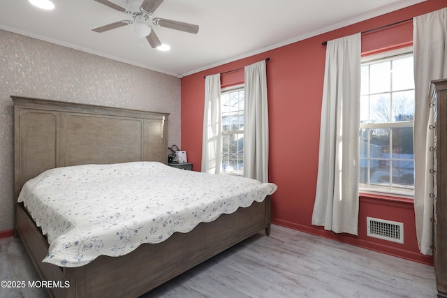 bedroom featuring crown molding, visible vents, light wood-style flooring, ceiling fan, and baseboards