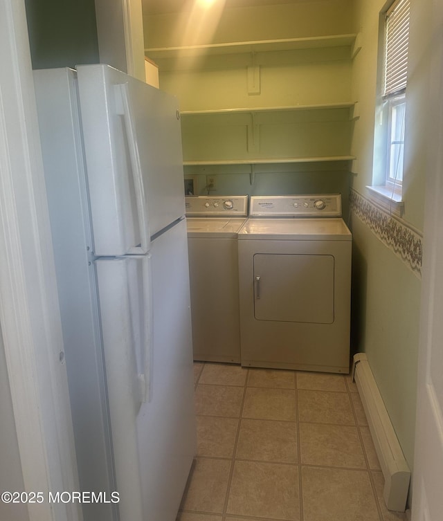 clothes washing area featuring laundry area, a baseboard radiator, light tile patterned floors, and washing machine and dryer