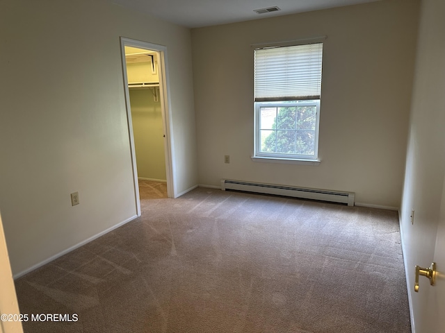 unfurnished bedroom featuring light colored carpet, visible vents, baseboards, a spacious closet, and baseboard heating