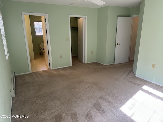 unfurnished bedroom featuring baseboards, connected bathroom, light colored carpet, a walk in closet, and a closet