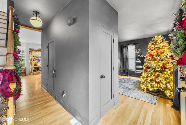 hallway with a healthy amount of sunlight, visible vents, and wood finished floors