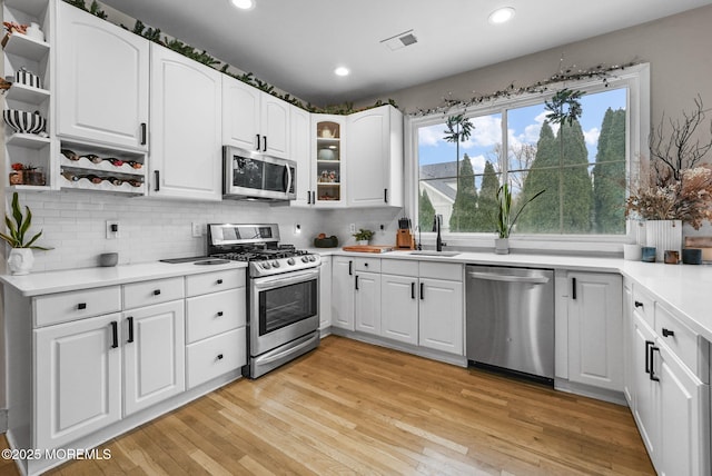 kitchen with visible vents, white cabinets, light countertops, appliances with stainless steel finishes, and open shelves