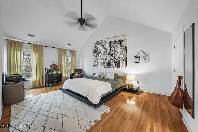 bedroom with a ceiling fan, visible vents, baseboards, and wood finished floors