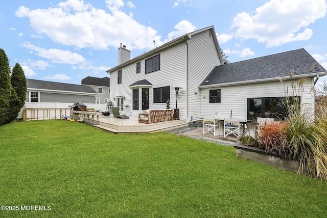 rear view of house with a chimney, a yard, a deck, and fence