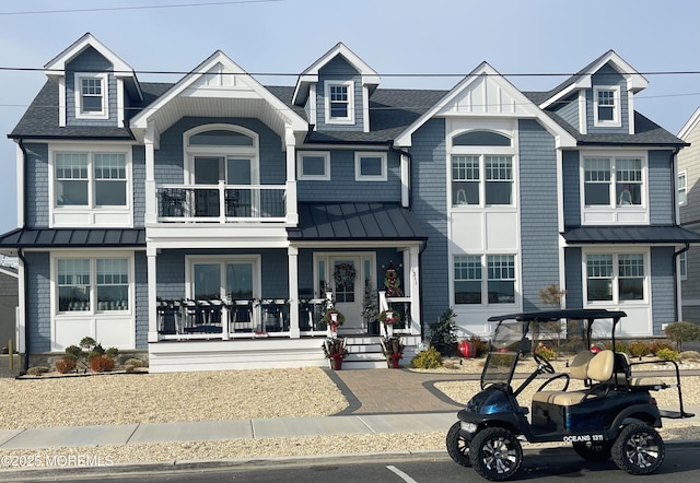 view of front of property featuring a standing seam roof, a shingled roof, metal roof, and a porch