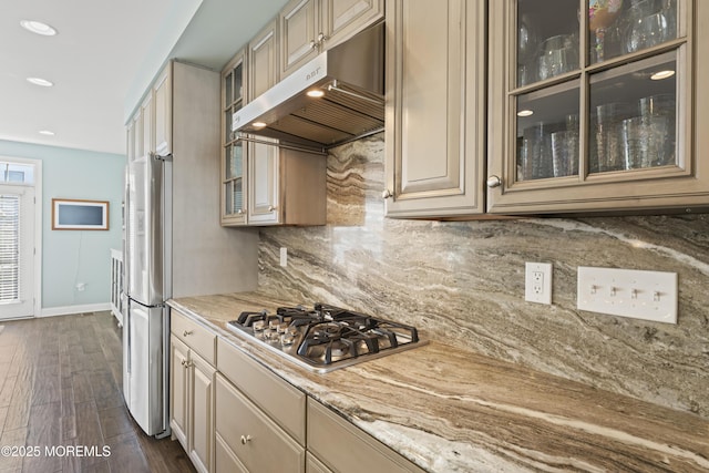 kitchen featuring decorative backsplash, appliances with stainless steel finishes, dark wood-type flooring, glass insert cabinets, and under cabinet range hood