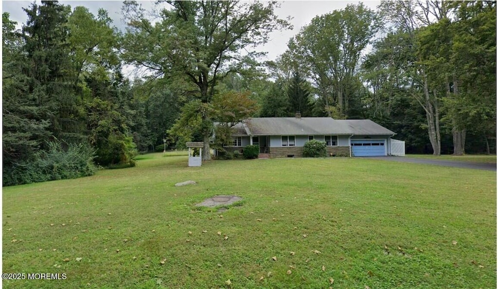 single story home featuring a front yard, driveway, a chimney, and an attached garage