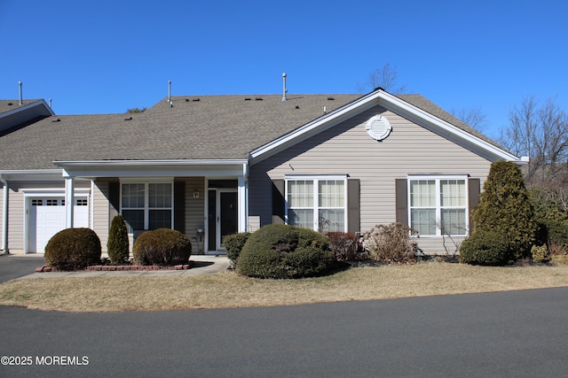 ranch-style house with roof with shingles, driveway, and an attached garage