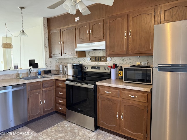 kitchen with under cabinet range hood, stainless steel appliances, light countertops, and decorative light fixtures