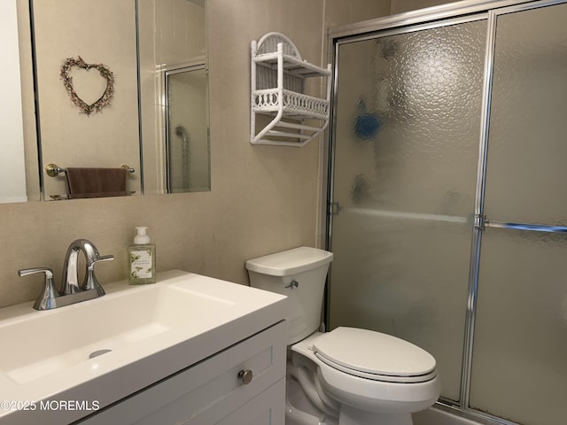 bathroom featuring a shower with door, vanity, and toilet