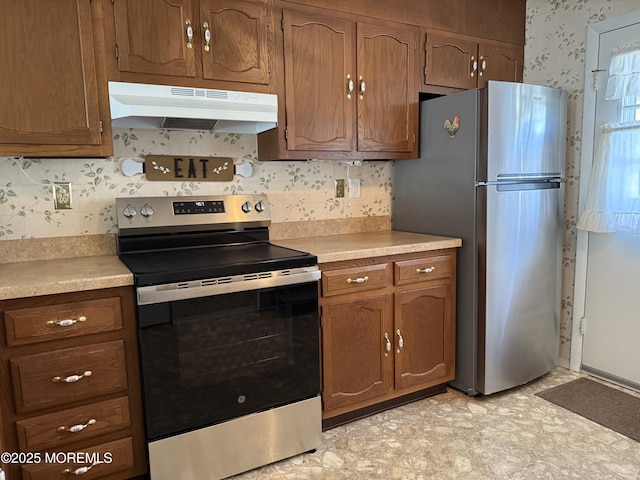 7B Cambridge Cir Unit B, Manchester, NJ 08759 - kitchen with appliances with stainless steel finishes, under cabinet range hood, wallpapered walls, light countertops, and brown cabinets