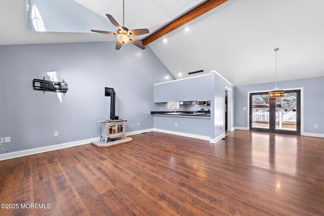 unfurnished living room featuring a wood stove, beam ceiling, high vaulted ceiling, and dark wood-style flooring