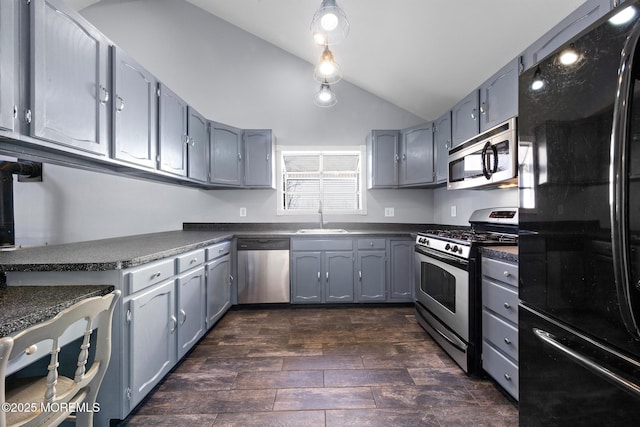 kitchen with appliances with stainless steel finishes, dark countertops, a sink, and lofted ceiling