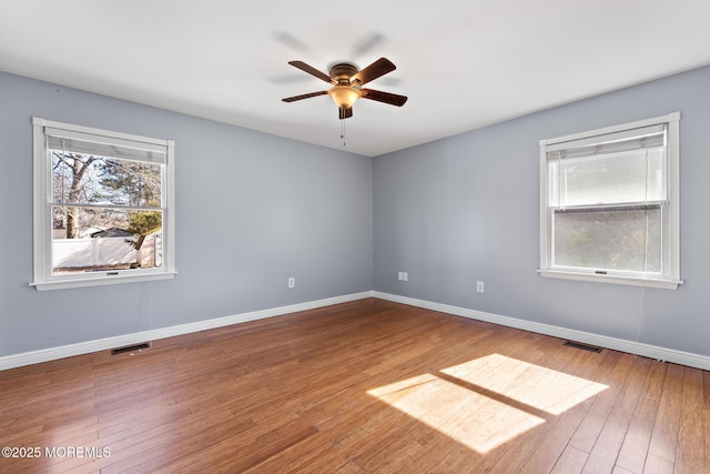 spare room with visible vents, baseboards, and wood finished floors