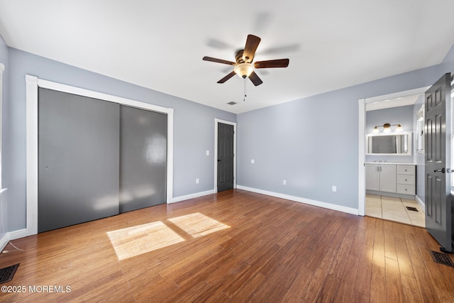 unfurnished bedroom featuring light wood-style flooring, connected bathroom, visible vents, and baseboards