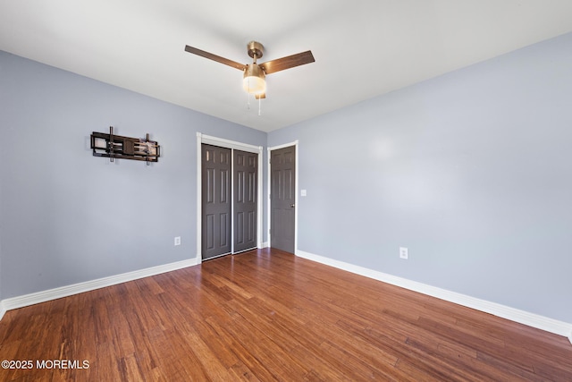 unfurnished bedroom with ceiling fan, a closet, wood finished floors, and baseboards