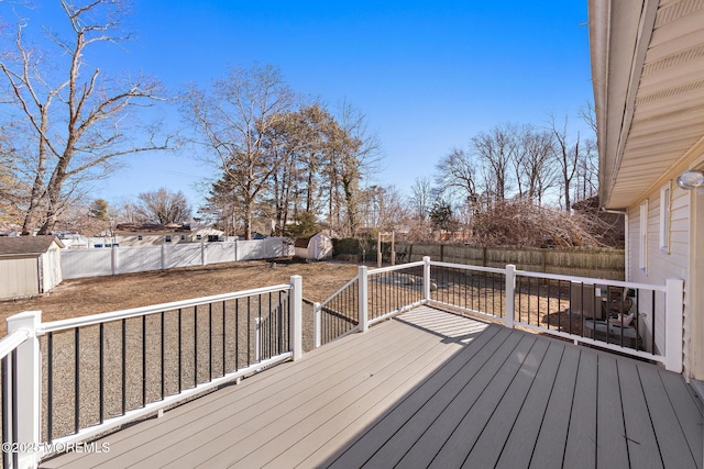 wooden deck with an outbuilding, a fenced backyard, and a shed