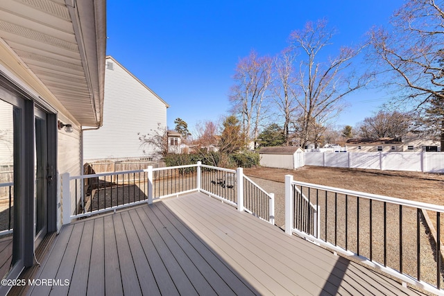 wooden deck featuring a shed, a fenced backyard, and an outdoor structure