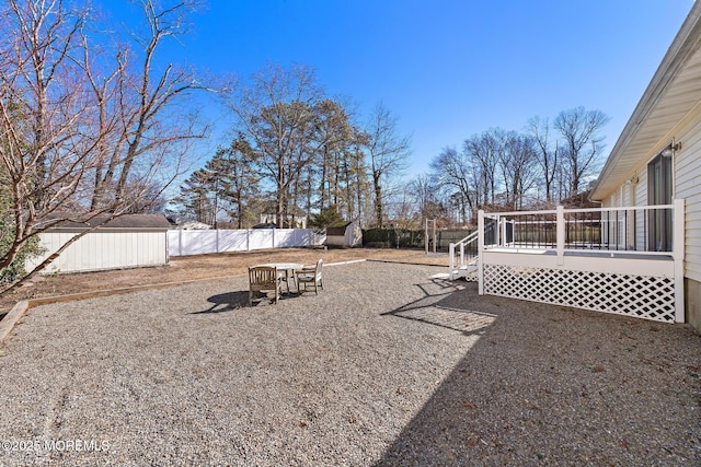 view of yard featuring an outbuilding, a storage unit, a fenced backyard, and a deck