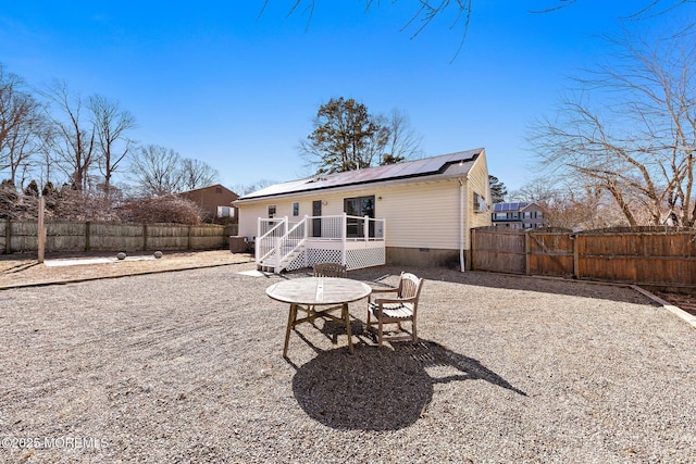 back of house with solar panels, crawl space, and a fenced backyard