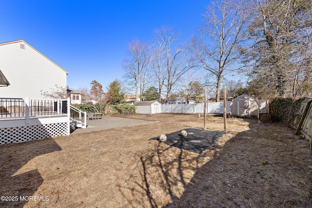 view of yard with a storage shed, a fenced backyard, an outdoor structure, and a wooden deck