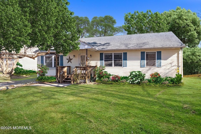 ranch-style house featuring roof with shingles, a front yard, and a wooden deck