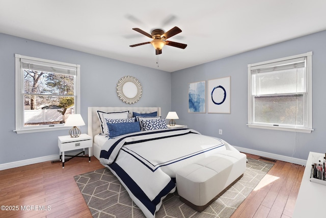 bedroom featuring ceiling fan, wood finished floors, visible vents, and baseboards