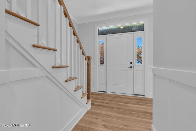 foyer featuring light wood-style floors, stairs, and crown molding