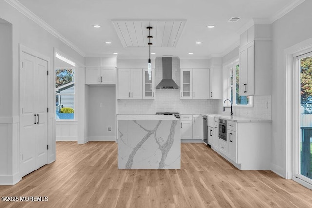 kitchen with glass insert cabinets, wall chimney exhaust hood, a kitchen island, and white cabinetry