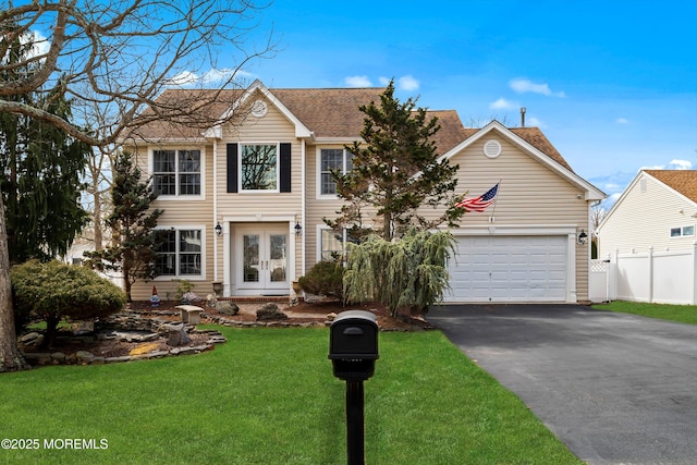 colonial-style house featuring a front yard, fence, driveway, french doors, and a garage