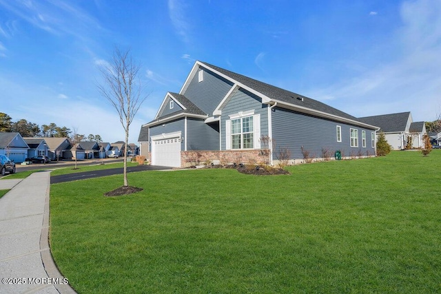 view of side of property featuring aphalt driveway, a residential view, a yard, and an attached garage