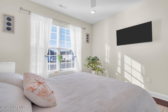 bedroom with baseboards, wood finished floors, visible vents, and a ceiling fan