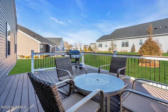 wooden deck featuring a residential view, grilling area, a lawn, and outdoor dining space