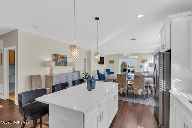 kitchen with dark wood-type flooring, freestanding refrigerator, open floor plan, and a kitchen breakfast bar