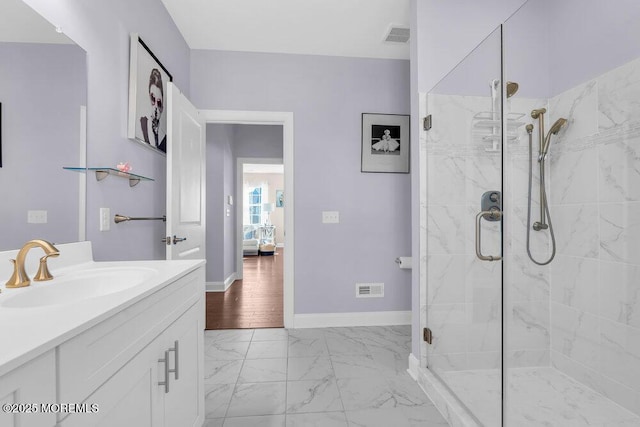 bathroom featuring marble finish floor, a shower stall, vanity, and baseboards