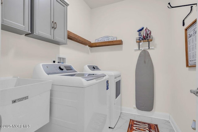 washroom featuring a sink, baseboards, marble finish floor, cabinet space, and washing machine and clothes dryer