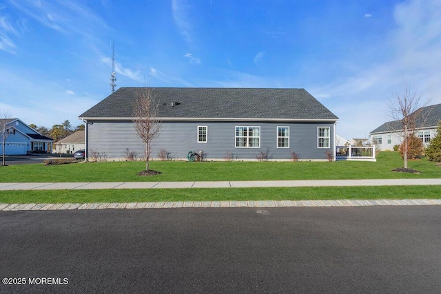 exterior space featuring a shingled roof and a front yard