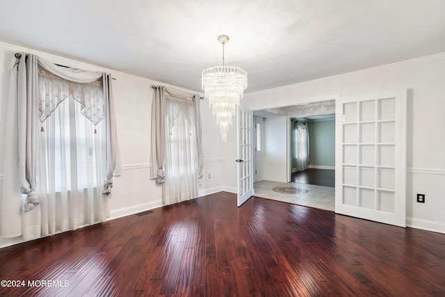 interior space with wood finished floors, visible vents, baseboards, ornamental molding, and an inviting chandelier