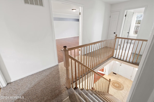 staircase featuring carpet floors, baseboards, and visible vents