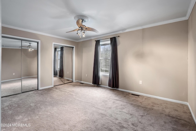 unfurnished bedroom with two closets, visible vents, ornamental molding, light carpet, and baseboards