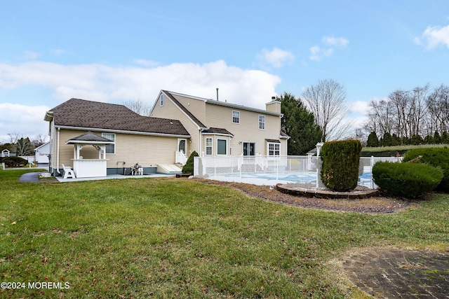 back of house with a lawn, a chimney, a swimming pool, and fence