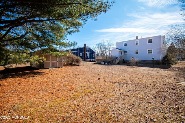 view of yard with a storage shed, stairway, a deck, and an outdoor structure