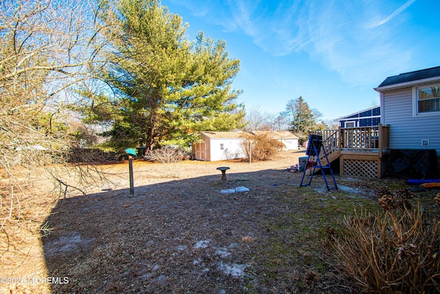 view of yard featuring an outdoor structure, a deck, and a storage shed